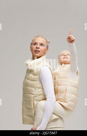 Virtuelle Technologie. Glücklich erfreut nettes Mädchen lächelnd und Blick auf die Kamera, während Mutter in ihren Armen in digitalen virtuellen Brille auf der Bienge hält Stockfoto