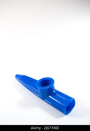 Blauer Kazoo, Kazoo ist ein Blasinstrument. Isoliert auf weißem Hintergrund. Platz kopieren, Platz für Text. Draufsicht. Keine Menschen, niemand. Vertikales Foto. Stockfoto