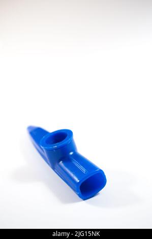 Blauer Kazoo, Kazoo ist ein Blasinstrument. Isoliert auf weißem Hintergrund. Platz kopieren, Platz für Text. Draufsicht. Keine Menschen, niemand. Vertikales Foto. Stockfoto