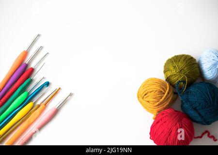 Draufsicht auf Häkelnadeln und Wollkugeln, bunte Häkelnadeln und Wollkugeln isoliert auf weißem Hintergrund. Flachbild. Speicherplatz kopieren. Stockfoto