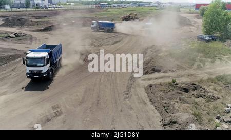 Jekaterinburg, Russland - August, 2021:der Bauprozess. Szene .große Lastwagen fahren und bauen etwas auf flachem Gelände neben der Stadt. High qu Stockfoto