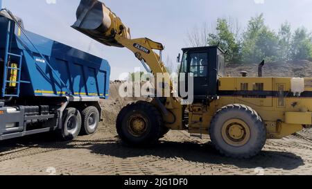 Jekaterinburg, Russland - August, 2021:der Bauprozess. Szene .große Lastwagen fahren und bauen etwas auf flachem Gelände neben der Stadt. High qu Stockfoto