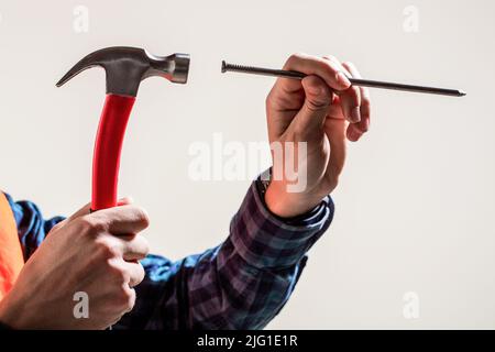 Hammer Hand Nagel. Die Hände des Männchens halten einen Hammer und ein Nageln. Hand mit Hammernageln. Hände mit Hammer und Nagel. Die Nägel schlagen, nur die Hände Stockfoto