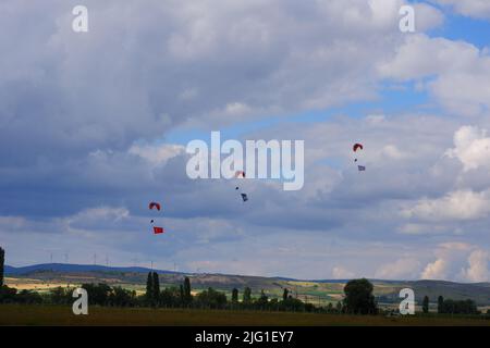 Drei Fallschirmspringer am bewölkten Himmel ziehen Flagge, Banner und Poster von Atatürk für eine Airshow in der Türkei Stockfoto