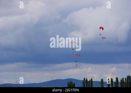 Drei Fallschirmspringer am bewölkten Himmel ziehen Flagge, Banner und Poster von Atatürk für eine Airshow in der Türkei Stockfoto