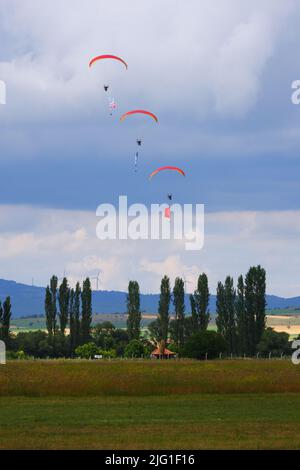 Drei Fallschirmspringer am bewölkten Himmel ziehen Flagge, Banner und Poster von Atatürk für eine Airshow in der Türkei Stockfoto