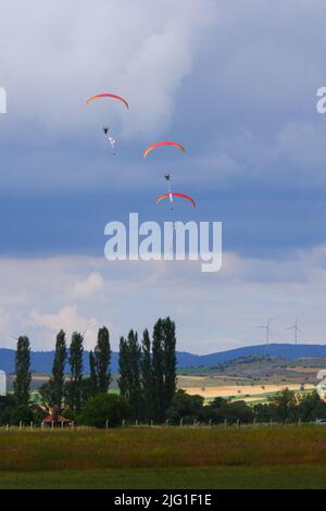 Drei Fallschirmspringer am bewölkten Himmel ziehen Flagge, Banner und Poster von Atatürk für eine Airshow in der Türkei Stockfoto