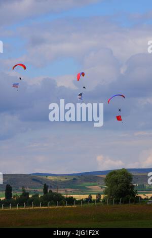 Drei Fallschirmspringer am bewölkten Himmel ziehen Flagge, Banner und Poster von Atatürk für eine Airshow in der Türkei Stockfoto