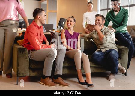 Glückliche multirassische Geschäftsleute und Geschäftsfrauen diskutieren im kreativen Büro Stockfoto