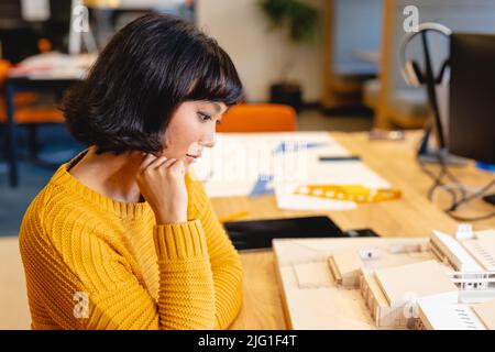 Biracial junge Architektin untersucht Architekturmodell in kreativen Büro Stockfoto