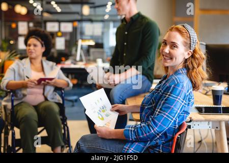 Porträt einer lächelnden jungen kaukasischen Geschäftsfrau mit Dokumenten während des Treffens im Büro Stockfoto