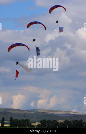 Drei Fallschirmspringer am bewölkten Himmel ziehen Flagge, Banner und Poster von Atatürk für eine Airshow in der Türkei Stockfoto