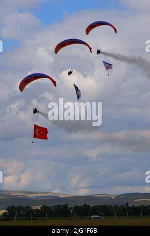 Drei Fallschirmspringer am bewölkten Himmel ziehen Flagge, Banner und Poster von Atatürk für eine Airshow in der Türkei Stockfoto