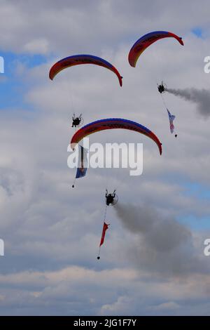 Drei Fallschirmspringer am bewölkten Himmel ziehen Flagge, Banner und Poster von Atatürk für eine Airshow in der Türkei Stockfoto