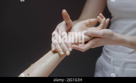 Frau genießen eine Zucker Meersalz natürlichen Körper Peeling Peeling Behandlung mit professioneller Kosmetikerin. Aktion. Konzept von Schönheit und Körperpflege Stockfoto