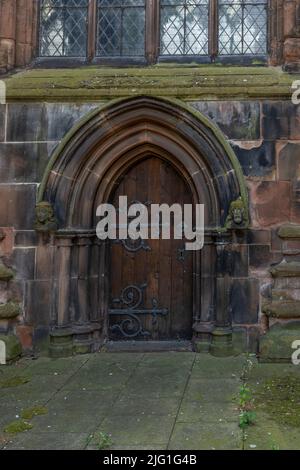 Alte Holztür auf einer Kirche mit verzierten Scharnieren, Schloss und rundem Griff Stockfoto