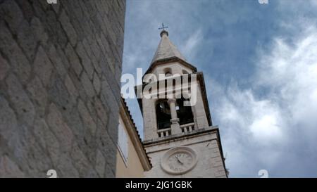 Blick von unten auf ein Turmgebäude mit einer Glocke auf einem wolkenblauen Himmel Hintergrund. Kreativ. Architekturkonzept, altes historisches Gebäude Stockfoto