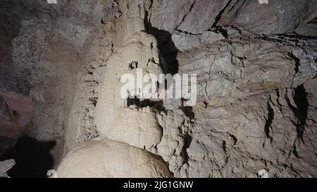 Unterirdische Höhlenformationen von Stalaktiten und Stalagmiten. Aktion. Blick in eine Höhle auf riesigen Steinwänden Stockfoto