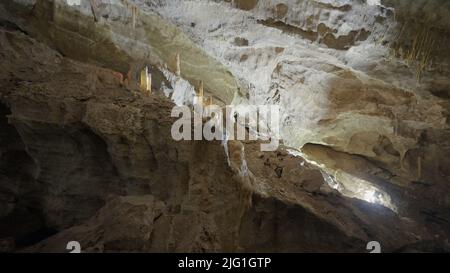 Unterirdische Höhlenformationen von Stalaktiten und Stalagmiten. Aktion. Blick in eine Höhle auf riesigen Steinwänden Stockfoto