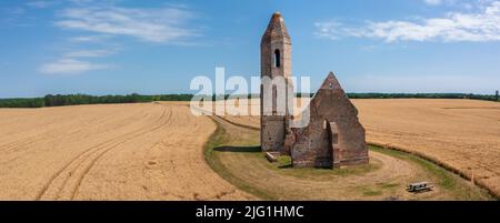 Somogyvámos, Ungarn - Panorama-Luftaufnahme über verlassene Kirchenruine namens Pusztatemplom in der Mitte eines landwirtschaftlichen Feldes. Stockfoto