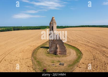 Somogyvámos, Ungarn - Luftaufnahme über verlassene Kirchenruine namens Pusztatemplom inmitten eines landwirtschaftlichen Feldes. Stockfoto