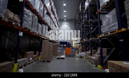 Moskau - Russland, 04.20.2022: Lager mit Kartons im Inneren auf Paletten Regale, Logistikzentrum. Kreativ. Riesige, große moderne Lagerhalle gefüllt wi Stockfoto