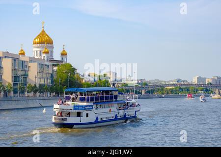 Moskau. Russland. 26. Juni 2021. Ein Ausflugsboot fährt entlang des Flusses Moskau an der orthodoxen Kathedrale von Christus dem Erlöser vorbei. Stockfoto