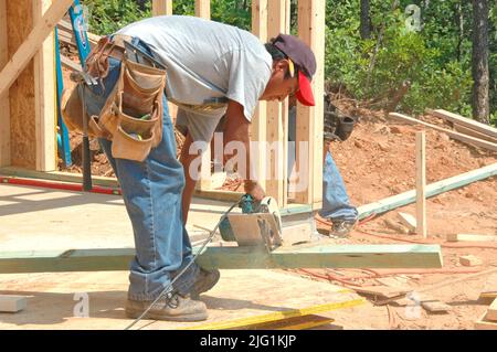 Lateinische Arbeit Besatzung Druckstoffen in Unasafe ohne Garde Gebäude Holzstab gebaut Haus Hause schneiden Maßnahme Nagelung an heißen Tag Stockfoto