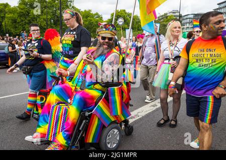 Lächelnder, verkleideter behinderter Mann in seinem Rollstuhl im Pride in London Stockfoto