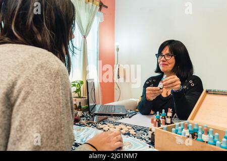 Naturopathische lateinische Erwachsene Ärztin in Konsultation, die Bachblütendropper zeigt und ihrem Patienten medizinische Anweisungen gibt. Stockfoto