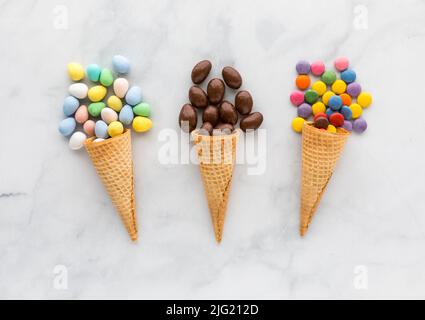 Waffelkegel gefüllt mit verschiedenen schokoladenbeschichteten Süßigkeiten. Stockfoto