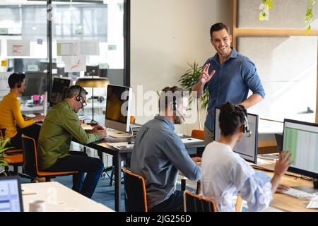 Lächelnder kaukasischer Manager motiviert Kundendienstmitarbeiter im Büro Stockfoto