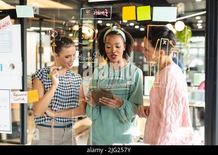 Weibliche Kollegen aus verschiedenen Rassen diskutieren im Büro über die Geschäftsstrategie eines Tablet-pcs Stockfoto