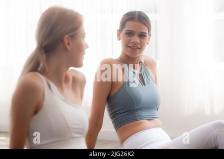 Zwei junge Menschen Frau üben Übung oder Yoga auf der Matte, während Sie Laptop-Computer-Tutorial online zu Hause, Frau mit Motivation suchen Notiz Stockfoto