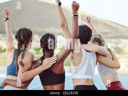 Rückansicht der stolzen begeisterten Olympiasieger, die sich in Einheit umarmen und jubeln. Aktives junges Team freut sich nach dem Sieg über einen Erfolg. Eine Gruppe Stockfoto