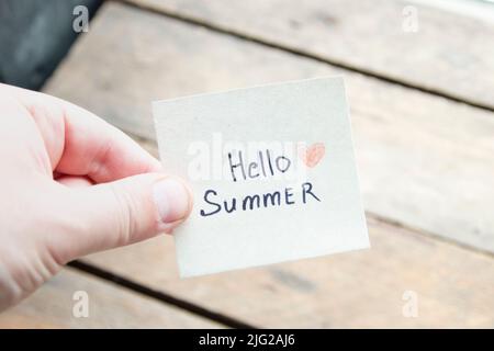 Hallo Sommer. Kreatives Konzept. Hand mit einem Anhänger mit der Aufschrift. Stockfoto