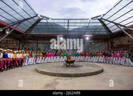 LIJIANG, CHINA - 7. JULI 2022 - Mosuo-Bewohner in ethnischen Kostümen tanzen für Touristen während einer Lagerfeuerparty am Lugu-See in Lijiang, Provinz Yunnan, Stockfoto
