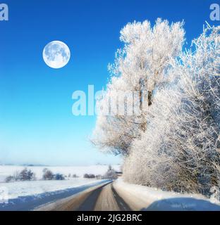 Der Mond in der Winterlandschaft. Straße mit Eis auf einer Winterlandschaft während der Mittagszeit. Der Mond scheint durch klare Wolken Stockfoto