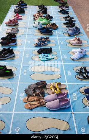 Nan, Thailand - 11. Dezember 2021: Schuhe und Sandalen auf blaues Bodenblech mit Zuweisungsblöcken in Thai-Stil Nummer ordentlich vor Restrikte gelegt Stockfoto