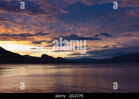 Malerischer Blick auf den farbenfrohen Sonnenuntergang über dem Okanagan Lake und den Bergen im Juni Stockfoto