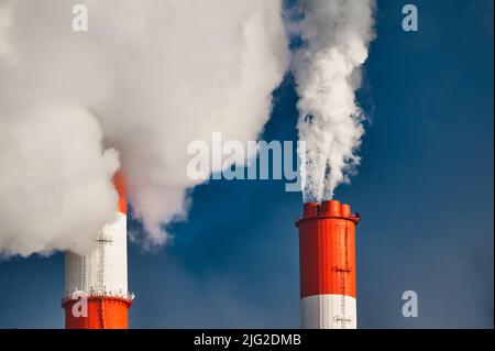 Schwere weiße Dampfwolken erheben sich über die Schornsteine der Pflanze Stockfoto