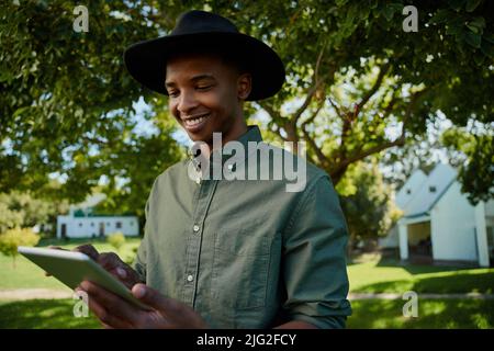 Gemischter Rassenbauer, der im Freien steht und auf einem digitalen Tablet tippt Stockfoto