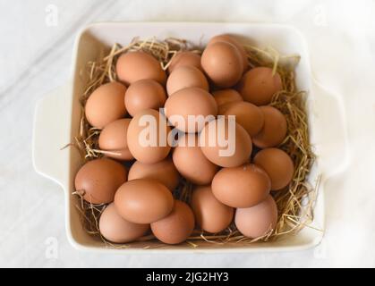 Haufen Eier auf Stroh in einer Pfanne in der Nähe Stockfoto