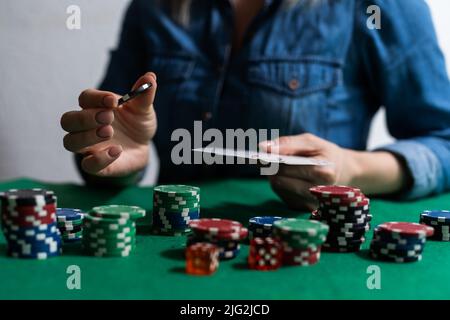 Eine Frau spielt in einem Casino. Öffnen von Karten, um Wetten zu erhöhen. Vor dem Hintergrund von Chips. Poker-Sieg Stockfoto