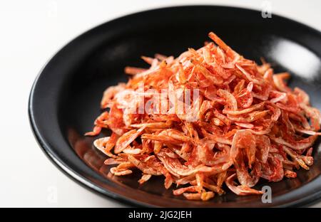 Getrocknete Sakura-Garnelen auf einem Teller auf weißem Hintergrund. Bild von japanischem Essen. Stockfoto