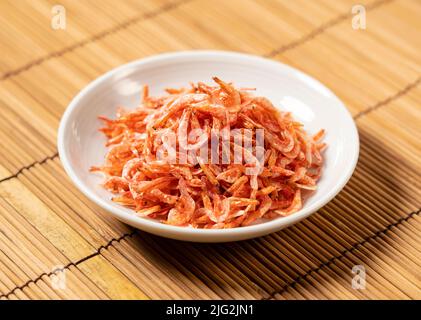 Getrocknete Sakura-Garnelen auf einem Teller, der auf einer Bambusluncheon-Matte platziert wurde. Bild von japanischem Essen. Stockfoto