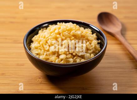 Tenkasu und Holzlöffel in einer Schüssel auf einem hölzernen Hintergrund serviert. Bild von japanischem Essen. Stockfoto