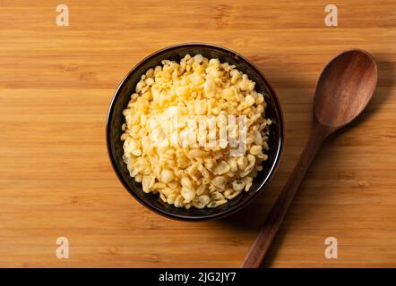 Tenkasu und Holzlöffel in einer Schüssel auf einem hölzernen Hintergrund serviert. Bild von japanischem Essen. Blick von oben. Stockfoto