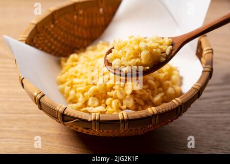 Tenkasu serviert in einem Sieb auf einem hölzernen Hintergrund mit einem Holzlöffel. Bild von japanischem Essen. Stockfoto