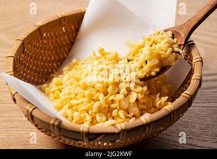 Tenkasu serviert in einem Sieb auf einem hölzernen Hintergrund mit einem Holzlöffel. Bild von japanischem Essen. Stockfoto